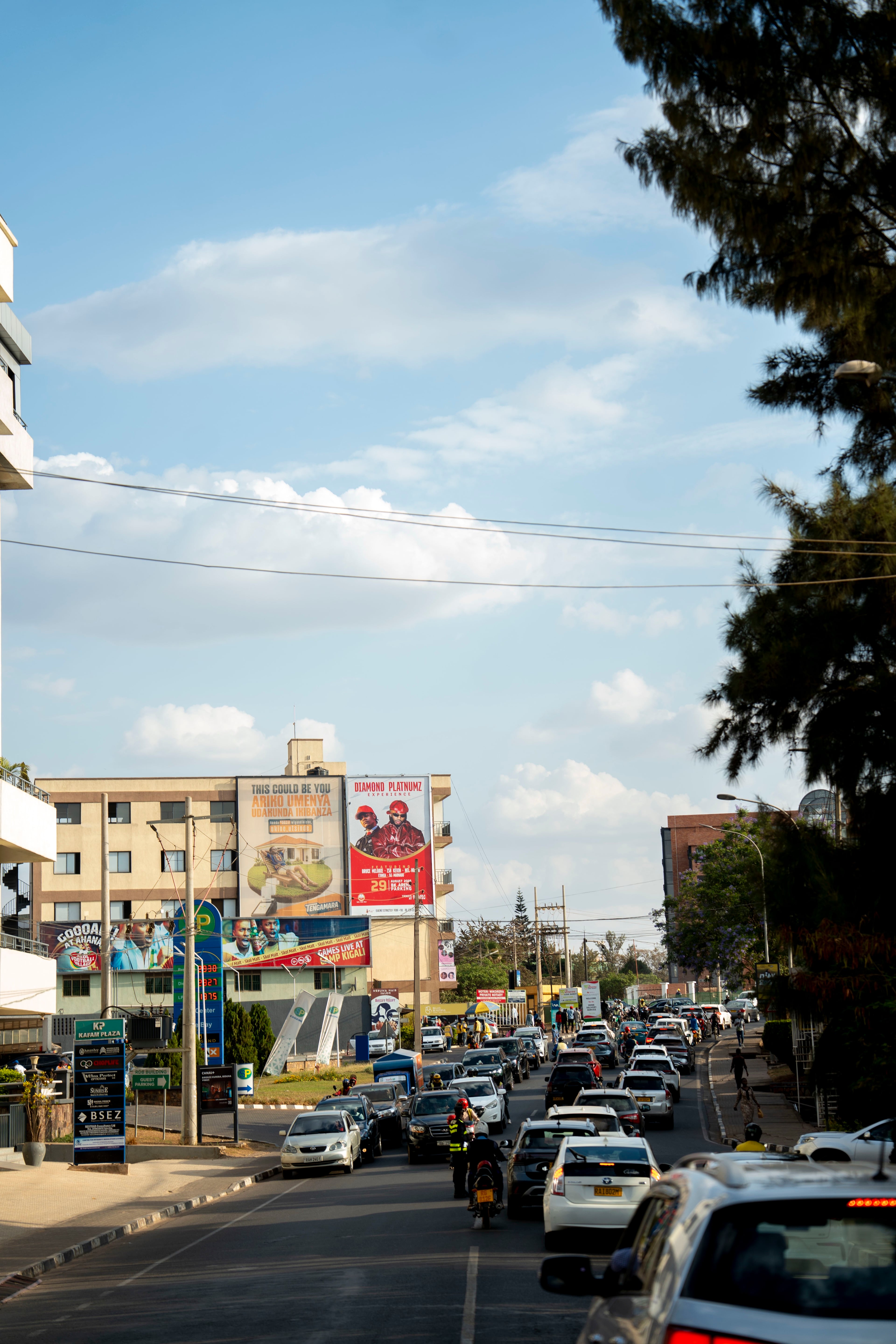 Quick Agency billboard on a busy street in Nyarutarama, Kigali, with heavy traffic and pedestrians
